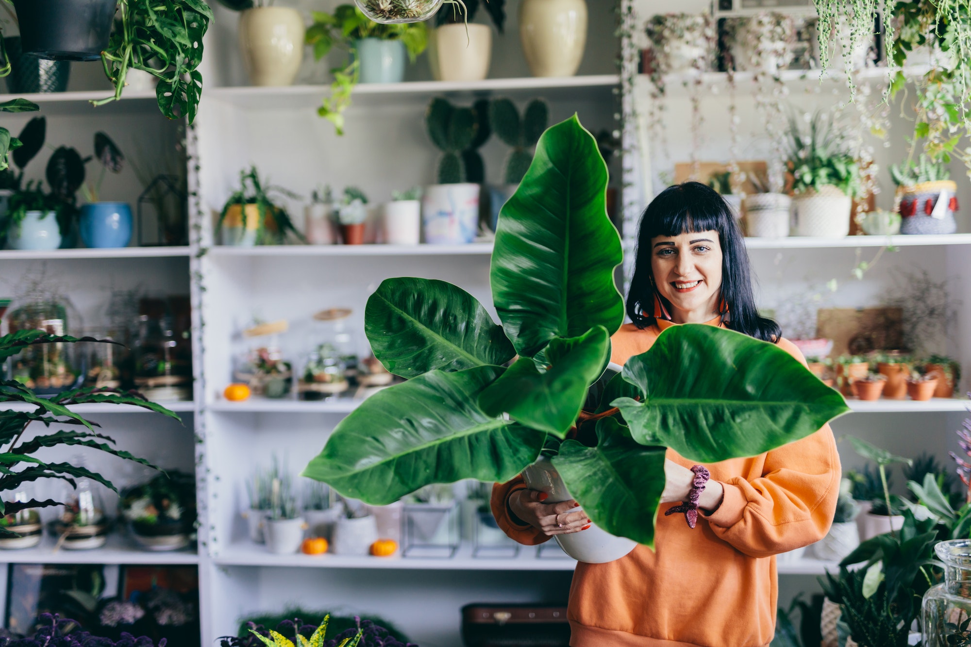 Woman holding big plant in the flower shop.